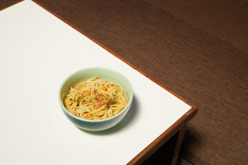 Bowl of Noodles With Vegetables Placed on a Wooden Table in a Cozy Indoor Setting