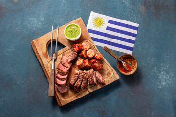 Celebrate Uruguay independence day with traditional asado featuring grilled meat, sausage, and sauce alongside the national flag