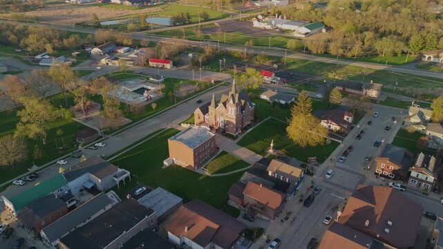 Drone video flying over New Glarus Wisconsin at sunset showing city buildings, rooftops, and the Swiss United Church of Christ in golden light.