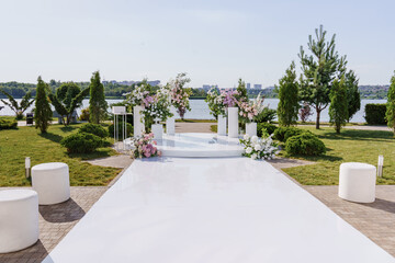 a path to the area of a wedding ceremony on the banks with columns and flowers.