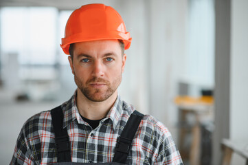 Construction worker wearing orange helmet and overalls in building under construction
