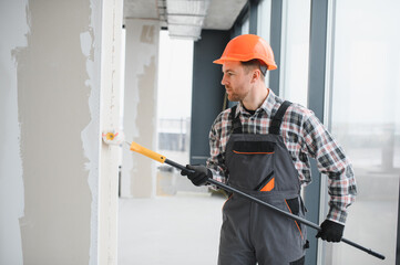 Construction worker applying primer on walls using paint roller