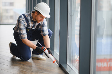Construction worker applying sealant to window frame