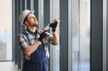 Construction worker applying sealant to window frame