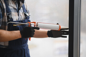 Construction worker applying sealant to window frame