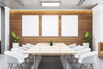 Modern conference room interior with wooden wall and three vertical blank canvas mockups above a wooden table and white chairs. 3D Rendering