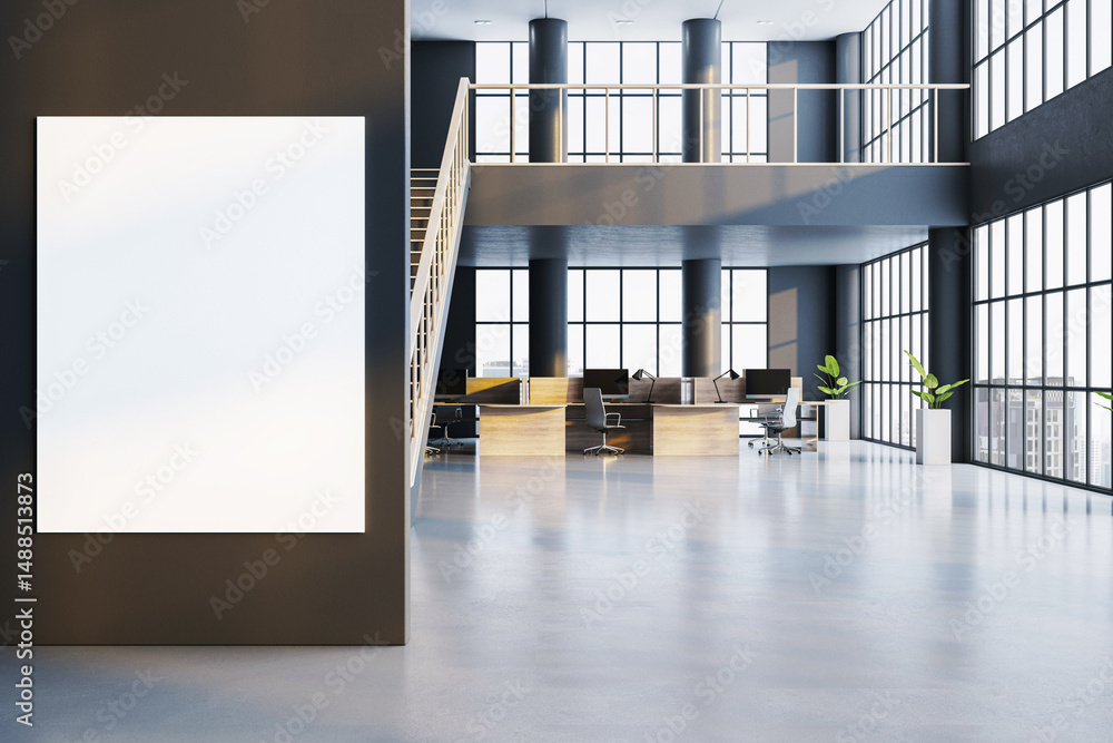 Poster vertical blank poster frame on dark wall in modern open space office interior with desks, computers,