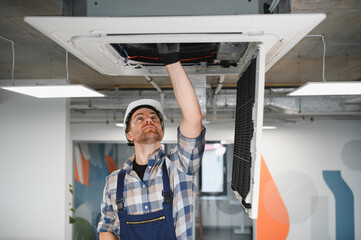 Hvac technician repairing air conditioning unit in office building