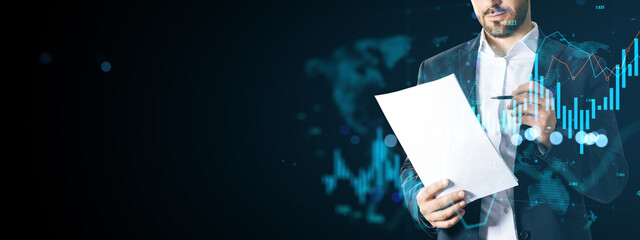 Businessman analyzing financial data with futuristic graphs and charts on abstract blue background symbolizing global economic analysis concept.