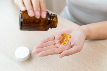 person prepare fish oil pills to her hands taking daily supplement