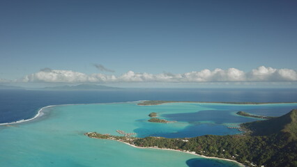 Aerial view revealing tropical island resort in Bora Bora, featuring overwater bungalows nestled...