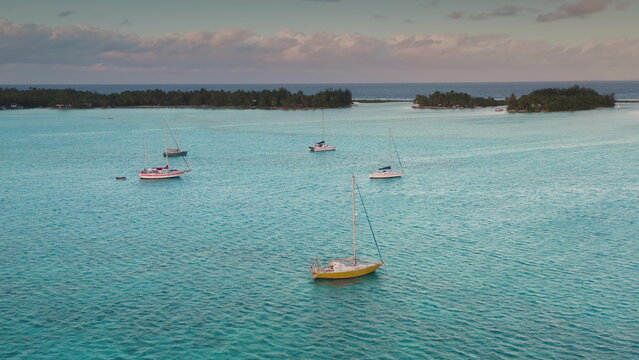 Serene turquoise waters enveloping lush tropical island, pristine sailboats anchored offshore, showcasing tranquil paradise with breathtaking scenic beauty of south pacific landscape