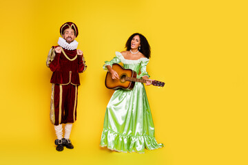 Couple in elegant vintage costumes posing on yellow background