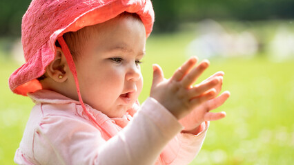 Baby girl clapping in the park in spring