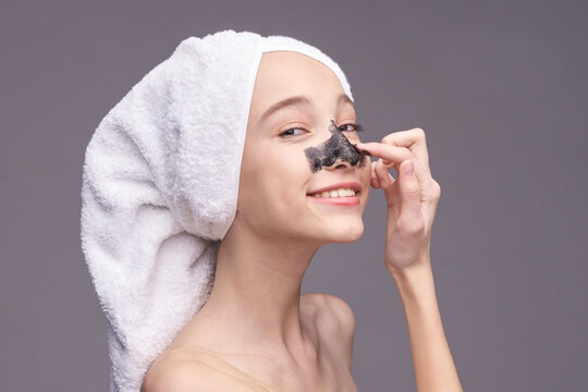 Young caucasian female applying blackhead remover with towel on hair smiling skincare routine.