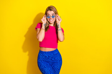 Obraz premium Cheerful young woman in colorful outfit posing against a vibrant yellow background, expressing happiness and charm