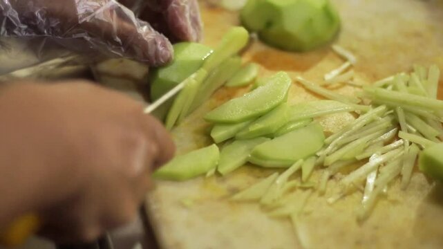 slicing chayote on cutting board 