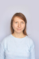Young caucasian female in light blue shirt against plain background.