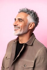 Fototapeta premium Pink solid background. Pattern art of style for aging men. Trendy men's wavy fringe haircut - midlife middle eastern man with short hair. A modern and happy gentleman enjoying his moment.