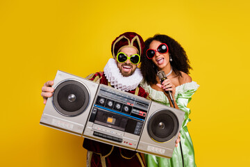 Cheerful couple dressed in vintage costumes enjoying a colorful theme party with retro props and...
