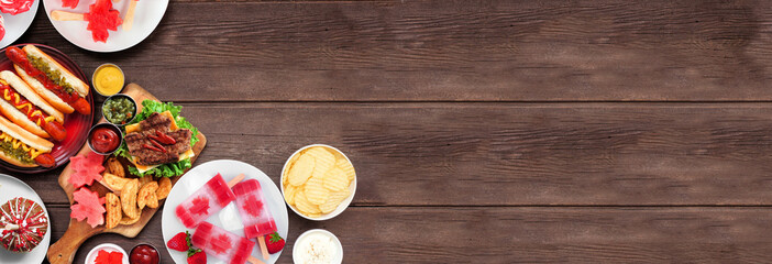 Canada Day patriotic food. Top view corner border on a dark wood banner background. Hot dogs, hamburgers and maple leaf red and white theme snacks. Copy space.