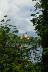 very small island on natural bled lake in summer with church in middle and beautiful green trees...