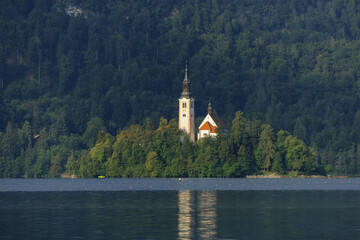 very small island on natural bled lake in summer with church in middle and beautiful lake...