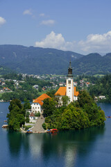 very small island on natural bled lake in summer with church in middle and beautiful green trees...