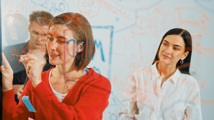 Professional business team brainstorming and working together about marketing project. Female caucasian leader writing idea on stick note while coworker present her idea confidently. Immaculate.