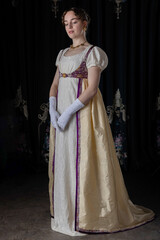 A Regency woman wearing evening attire, including an embroidered dress and a long spencer with...