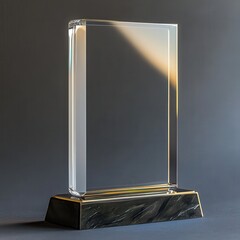 Clear glass award on black and gold base against gray background Showcase, ideal for recognition, achievement, or corporate event.