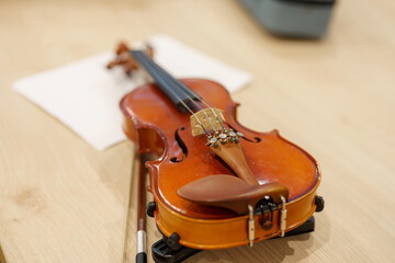 Fototapeta premium Beautifully crafted violin resting on a wooden surface during a music lesson in a cozy studio environment