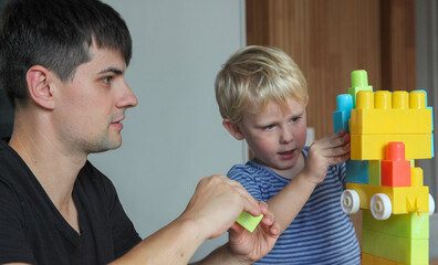 father and toddler son playing with plastic building blocks at home-bonding and creative learning