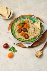 Appetizer, baked eggplant dip with yogurt on a green ceramic plate on a light concrete background. Served with cherry tomatoes, toasted bread and pine nuts. Recipes eggplant.