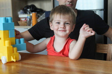 Fototapeta premium father and toddler son playing with plastic building blocks at home-bonding and creative learning
