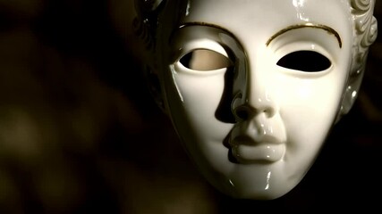 Intricate ceramic masquerade mask with delicate details, illuminated with elegant golden accents in a mysterious shadowy atmosphere. - Powered by Adobe