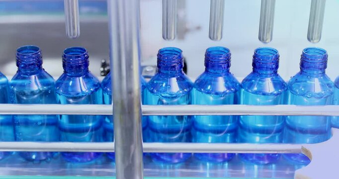 liquid filling line. pharmaceutical manufacturing line for liquid medicine, automatic bottle filling machine for syrup, sanitizer, or gel in plastic bottles at sterile industrial packaging facility