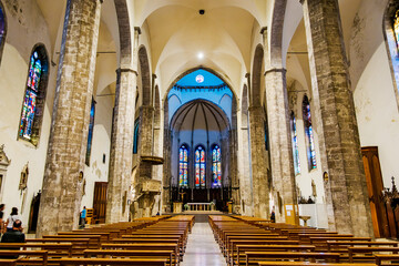 Interior of Cathedral of Saint Emidius with wooden pews, stained glass windows and stone columns, located in Ascoli Piceno, Italy, a beautiful example of Romanesque and Gothic architecture