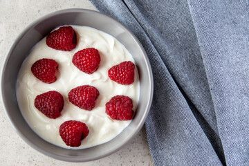 Gray bowl and natural yogurt with berries on the stone marble table.