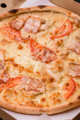 Italian pizza with chicken and bacon, cheese, tomatoes and sauce