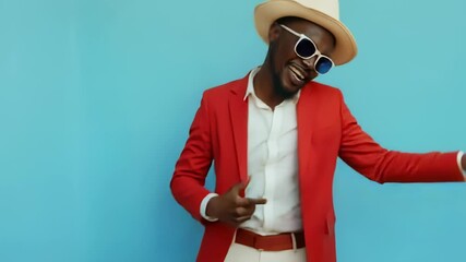 Stylish man in red blazer dancing joyfully against a blue background - Powered by Adobe
