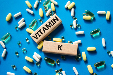 Vitamin K symbol. Concept word Vitamin K on wooden blocks. Beautiful blue background with pills....