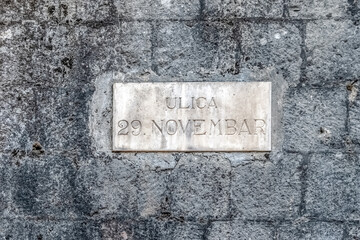 Street sign Ulica 29. Novembar on a stone wall in Kotor. The sign commemorates a historic date,...