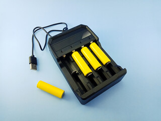white rechargeable batteries with charger on light blue background