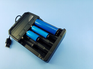 blue rechargeable batteries with charger on light blue background