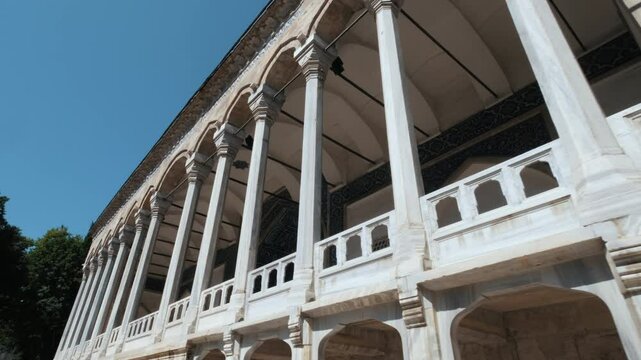 The impressive portico of the Tiled Kiosk in the Topkapi Palace in Istanbul, with its elegant marble columns and dazzling blue tiles, extending under the blue sky.