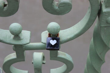 Black lock with white heart on bridge railing