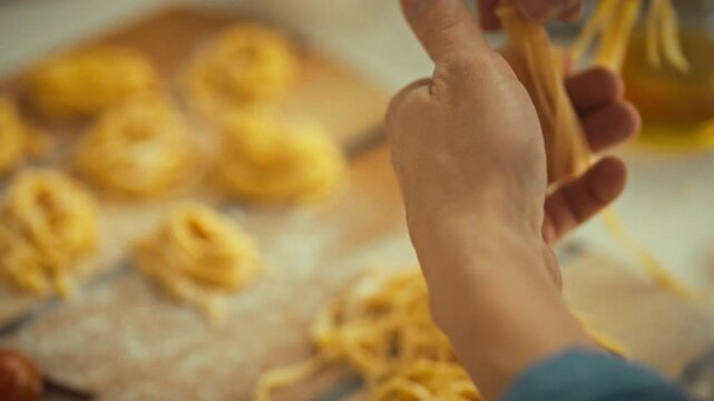 Hands skillfully twist strands of fresh pasta, surrounded by flour and other ingredients. This culinary activity takes place in a warm kitchen, celebrating the art of homemade cooking