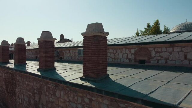 This image shows the brick chimneys and stone wall details of the caravanserai structure of Ilgın Lala Pasha Complex. Drone showing the regularly spaced chimneys.