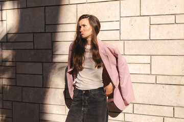 Drama business woman with wave long hair look sad at side. Girl wear pink jacket suit. Portrait of offended young girl with pouty lips wearing casual clothing standing.